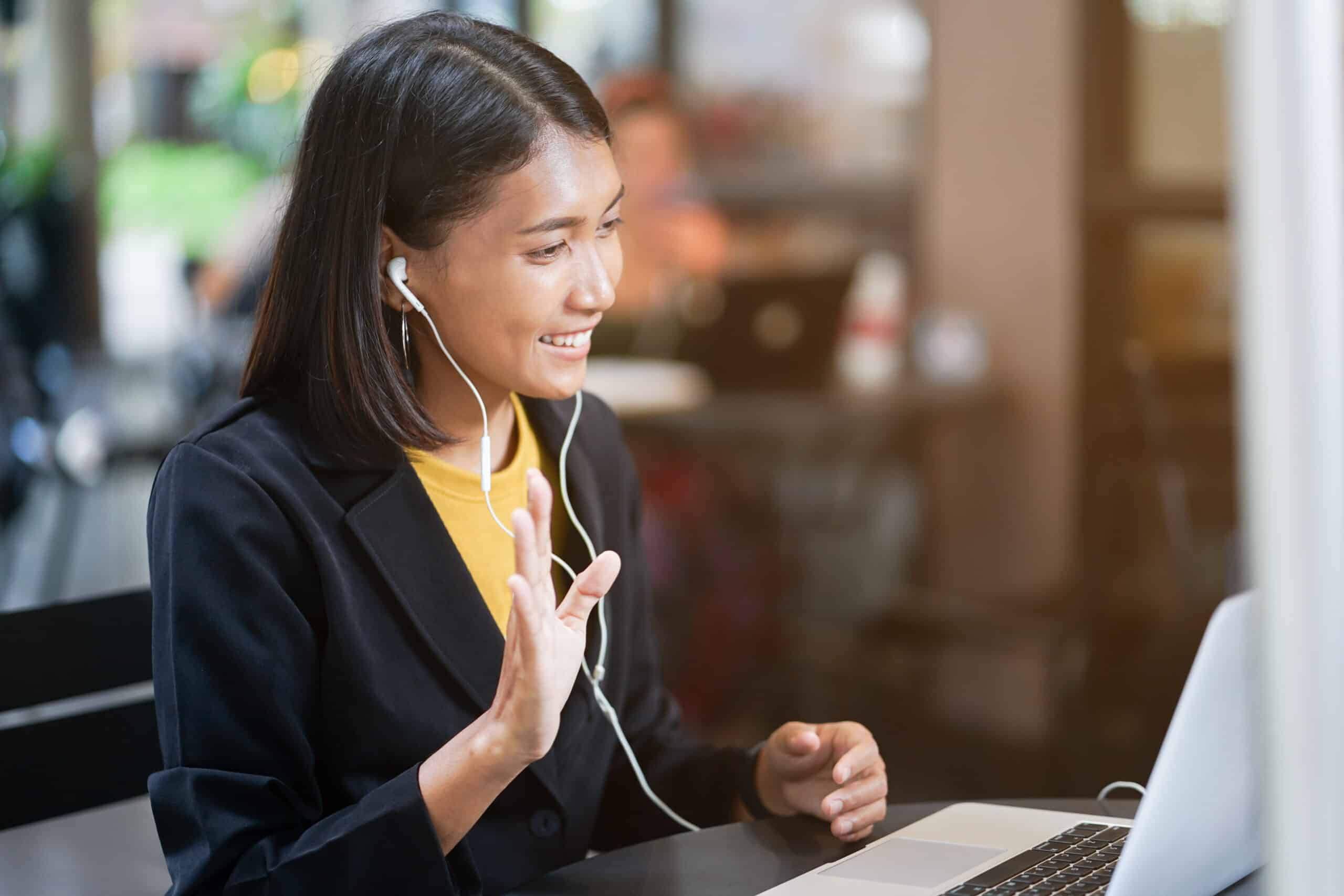 Professional wearing headphones smiling during a video call on her laptop