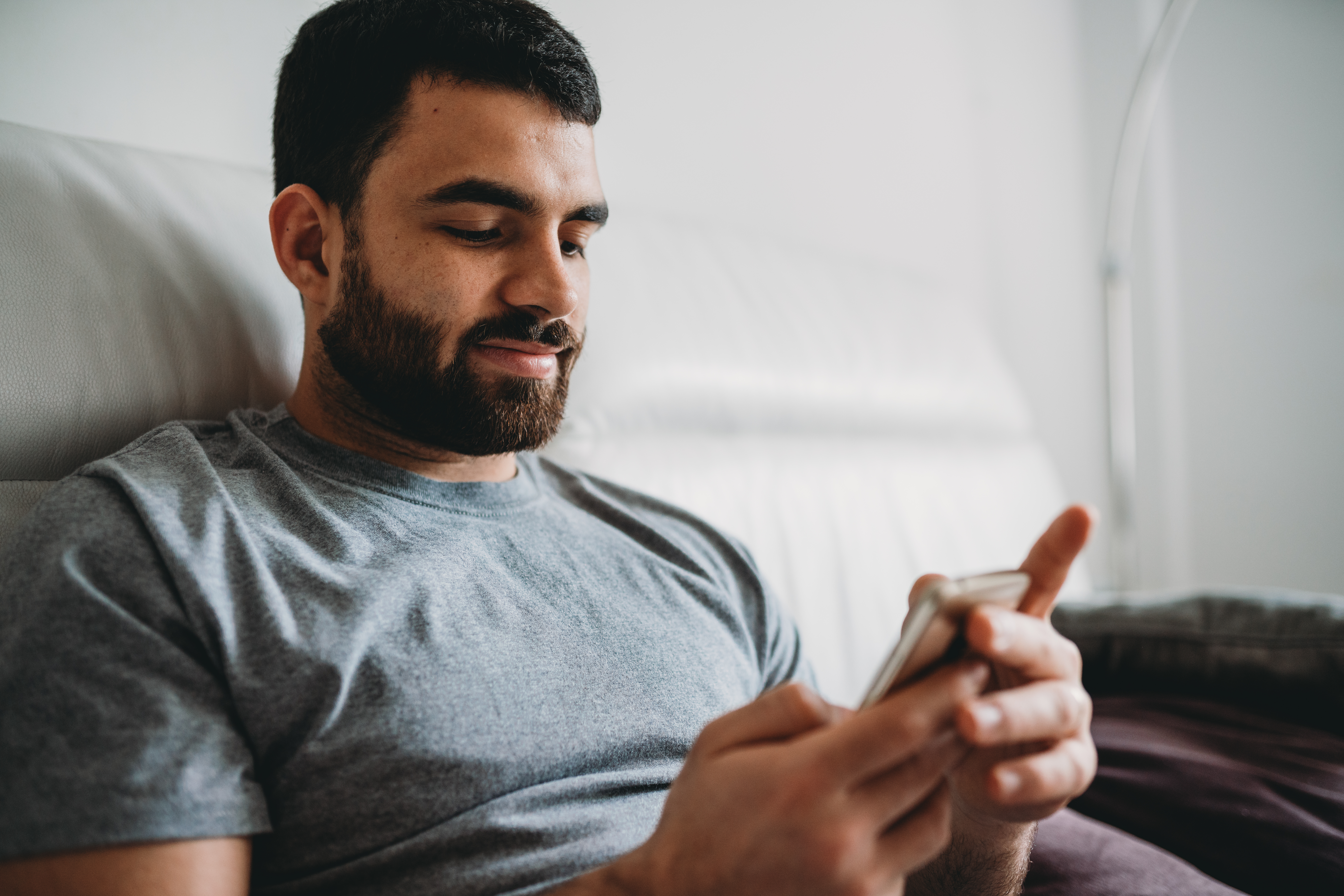 Man smiling while looking at his phone on the couch