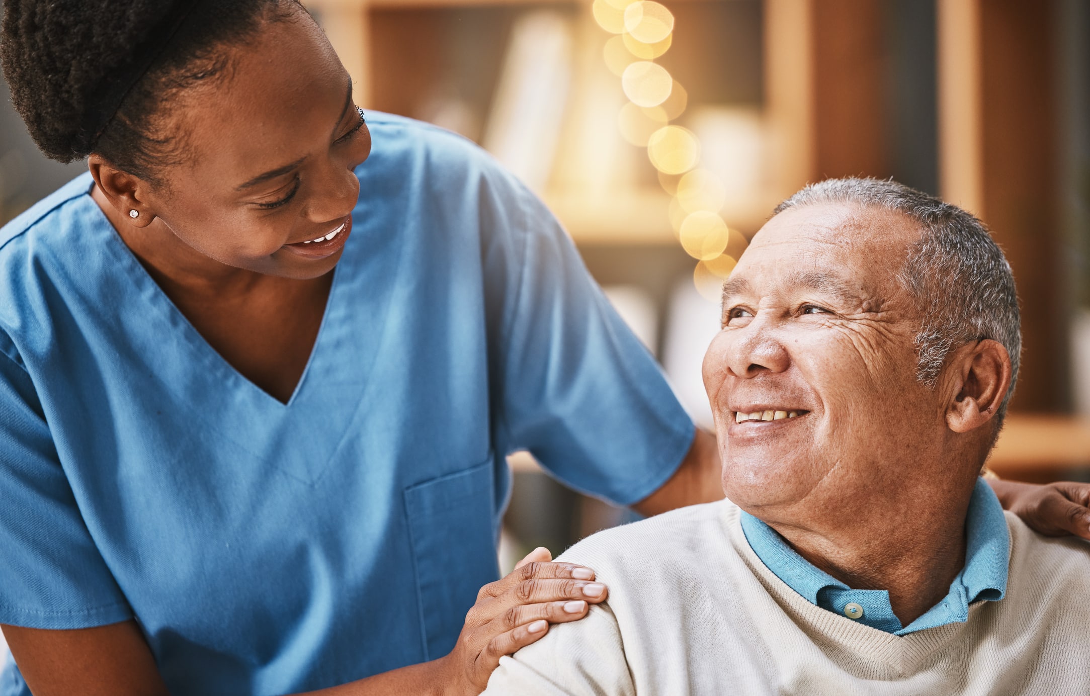 Caregiver with her hand on the shoulder of a smiling senior man