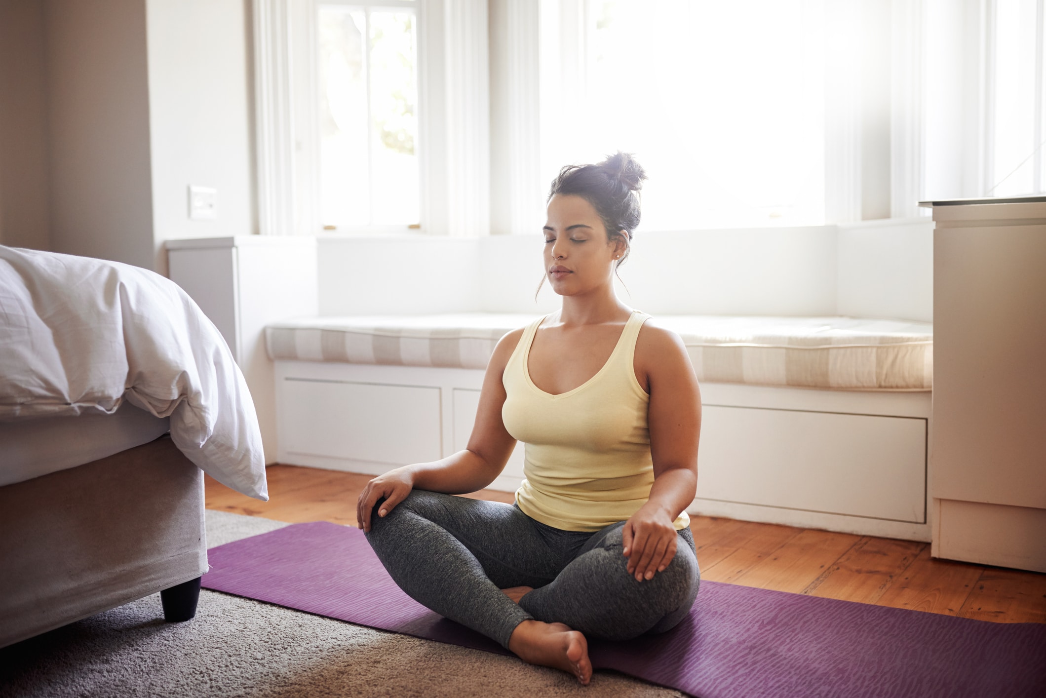 Woman meditating peacefully on a yoga mat at home
