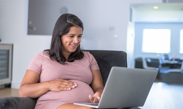 a woman in casual clothes smiling looking down at a laptop