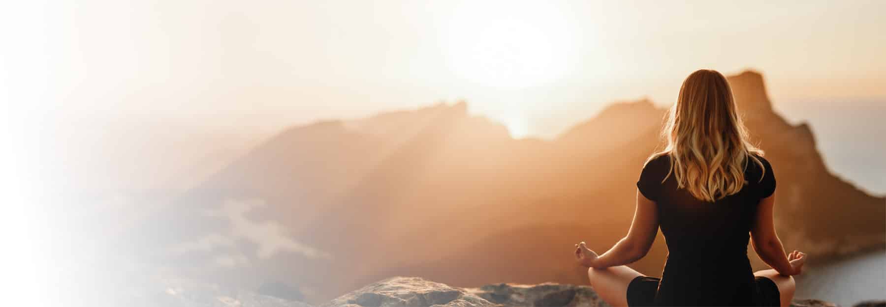 A woman meditating on a cliff