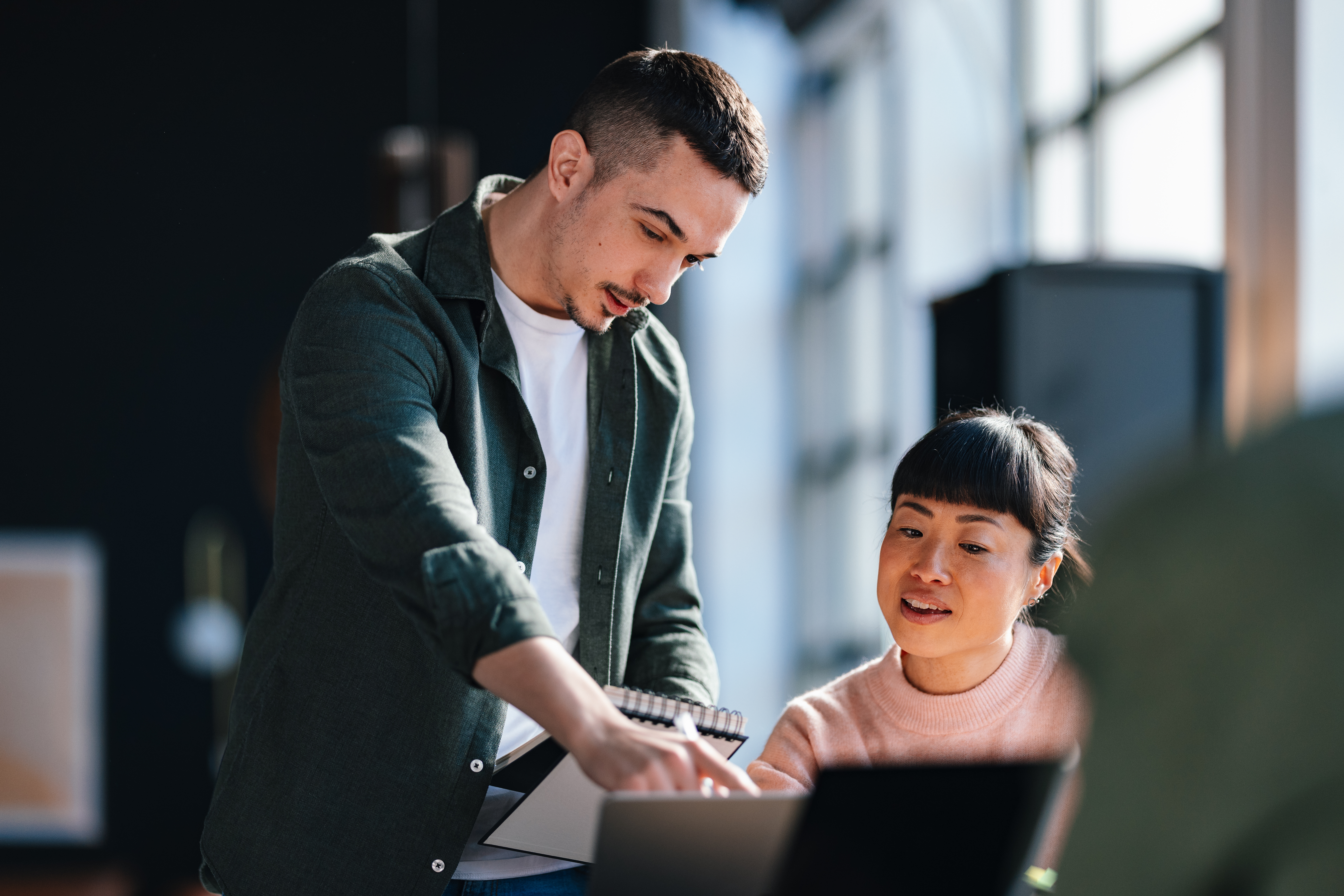 Man and woman talking with a notepad and a computer
