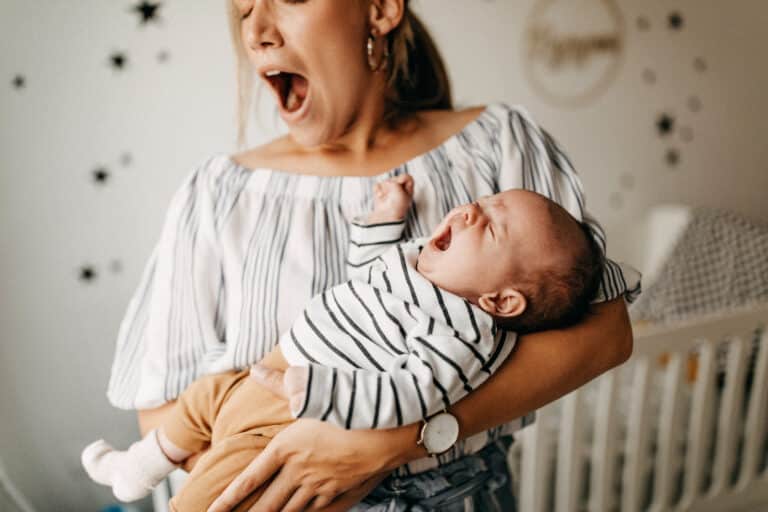 Women yawning while holding an infant